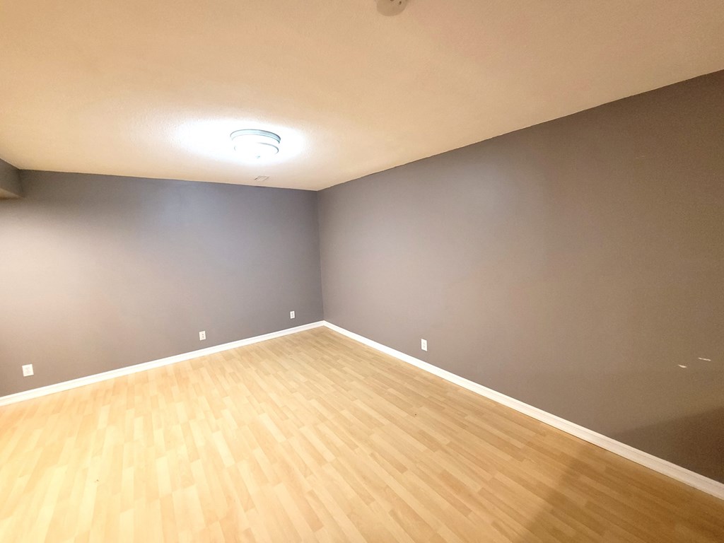 a empty room with a wooden floor and gray walls