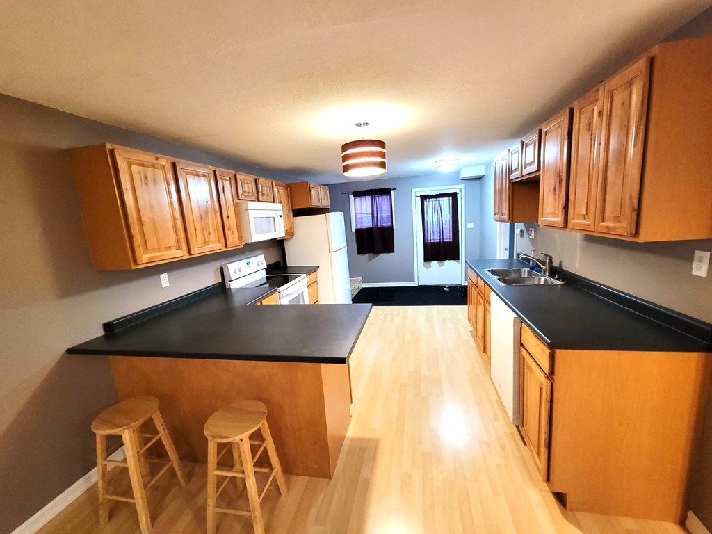 a kitchen with black counter tops and wooden cabinets