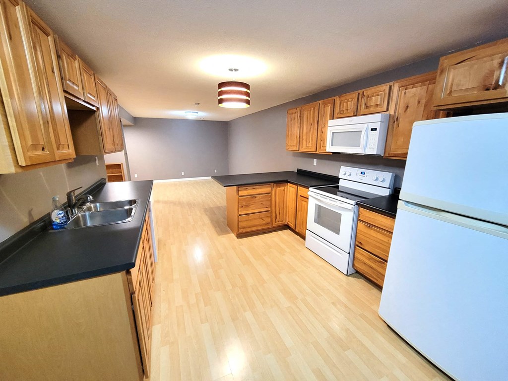 a large kitchen with wood flooring and white appliances