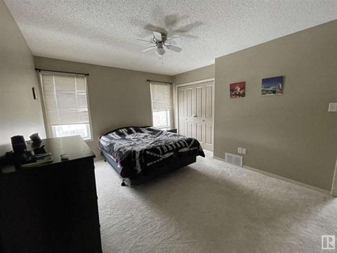A bedroom with a bed, dresser, and ceiling fan.