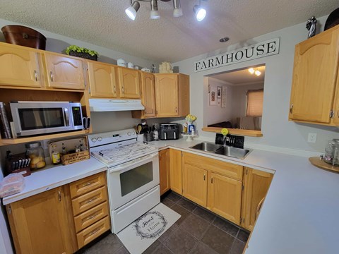 A kitchen with wooden cabinets and a sign that says Farmhouse.