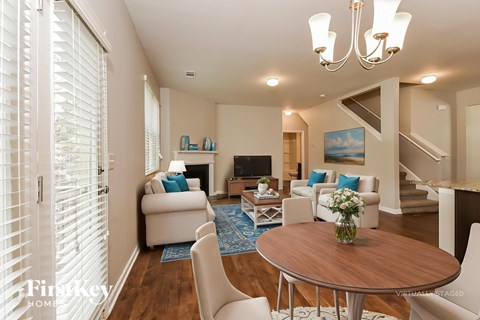 A living room with a wooden table and white chairs.