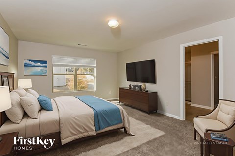 A bedroom with a bed, a chair, and a television.