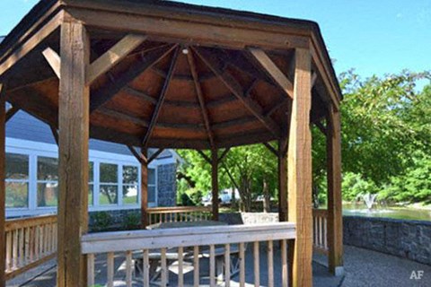 a wooden gazebo with a table and chairs on it
