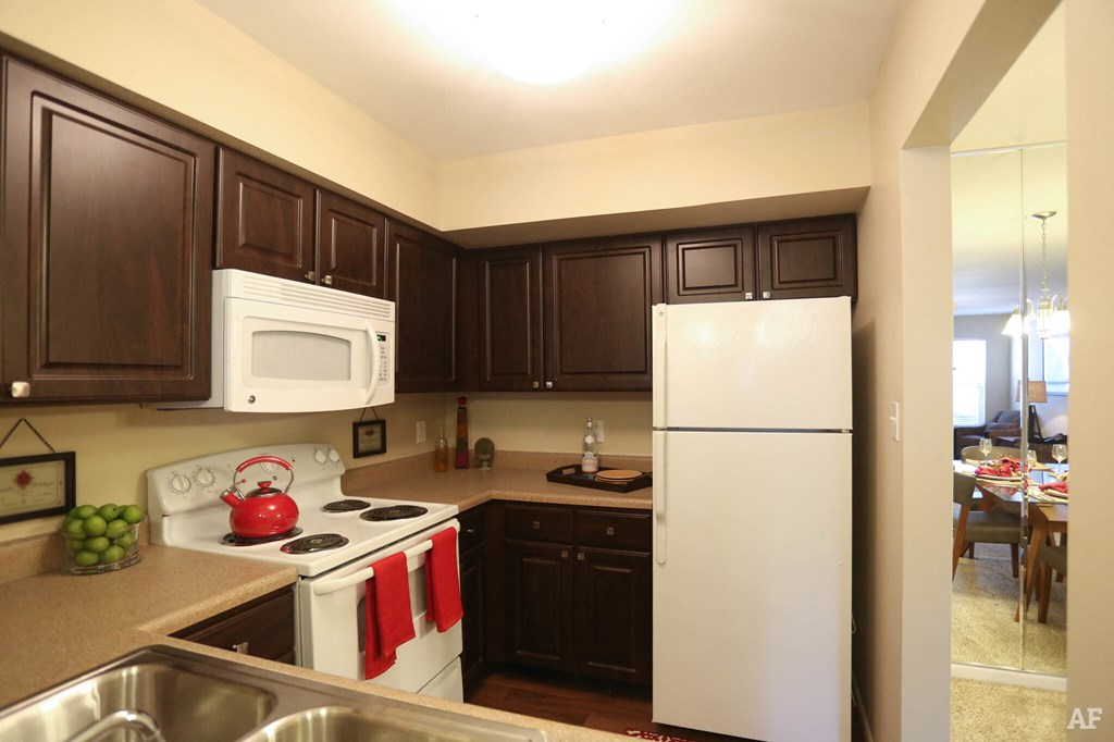 a large kitchen with white appliances and dark cabinets