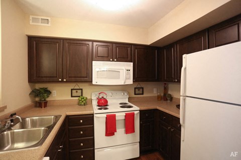 a kitchen with white appliances and dark cabinets