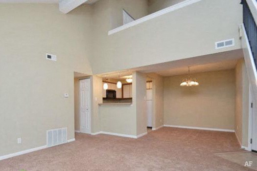 an empty living room with an open door to a kitchen