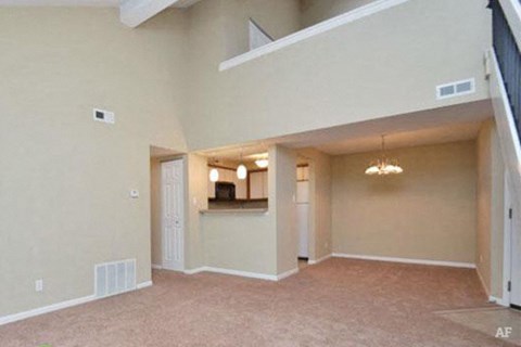 an empty living room with an open door to a kitchen