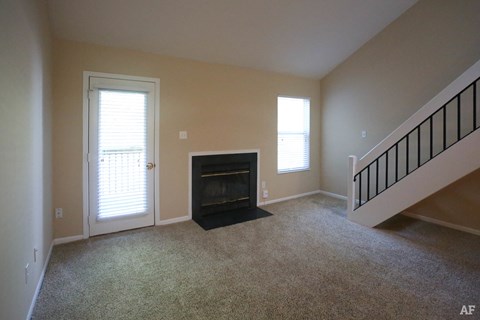 an empty living room with a fireplace and stairs