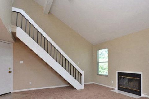 an empty living room with a staircase and a fireplace