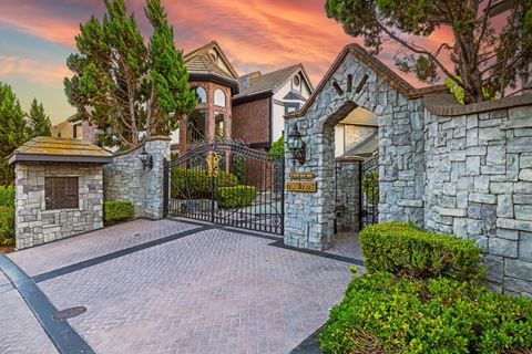 a mansion with a gate and stone walls and a driveway