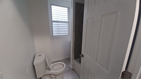 A white toilet in a small bathroom with a door to the right.