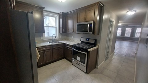 A kitchen with a black refrigerator, a black stove, and a black microwave.