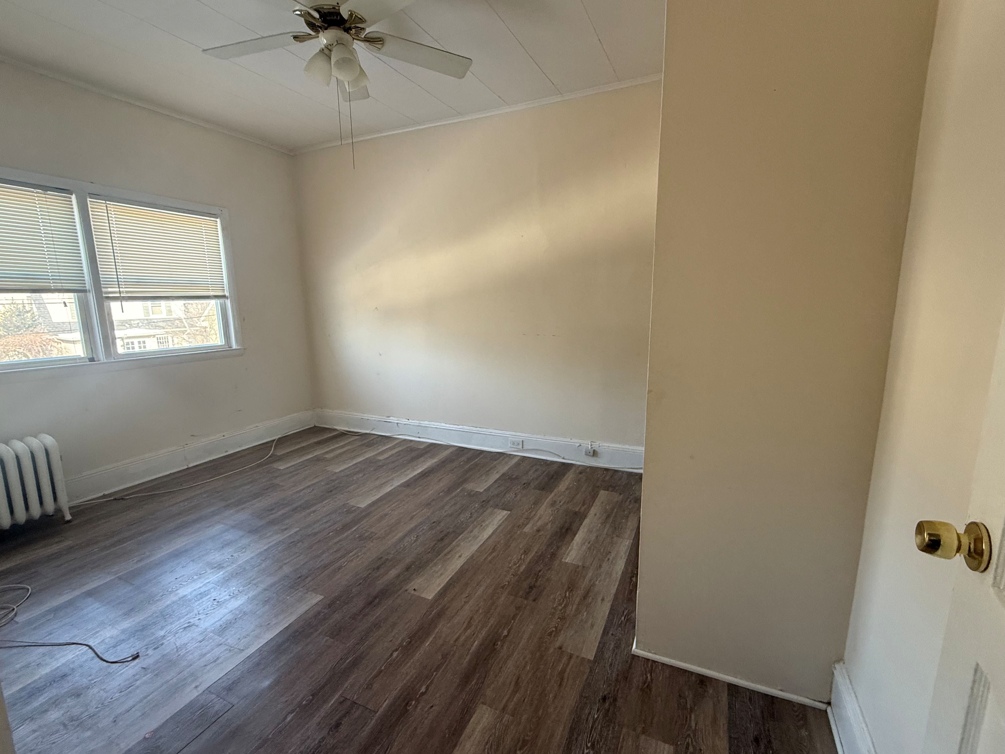 A room with a ceiling fan and wood flooring.