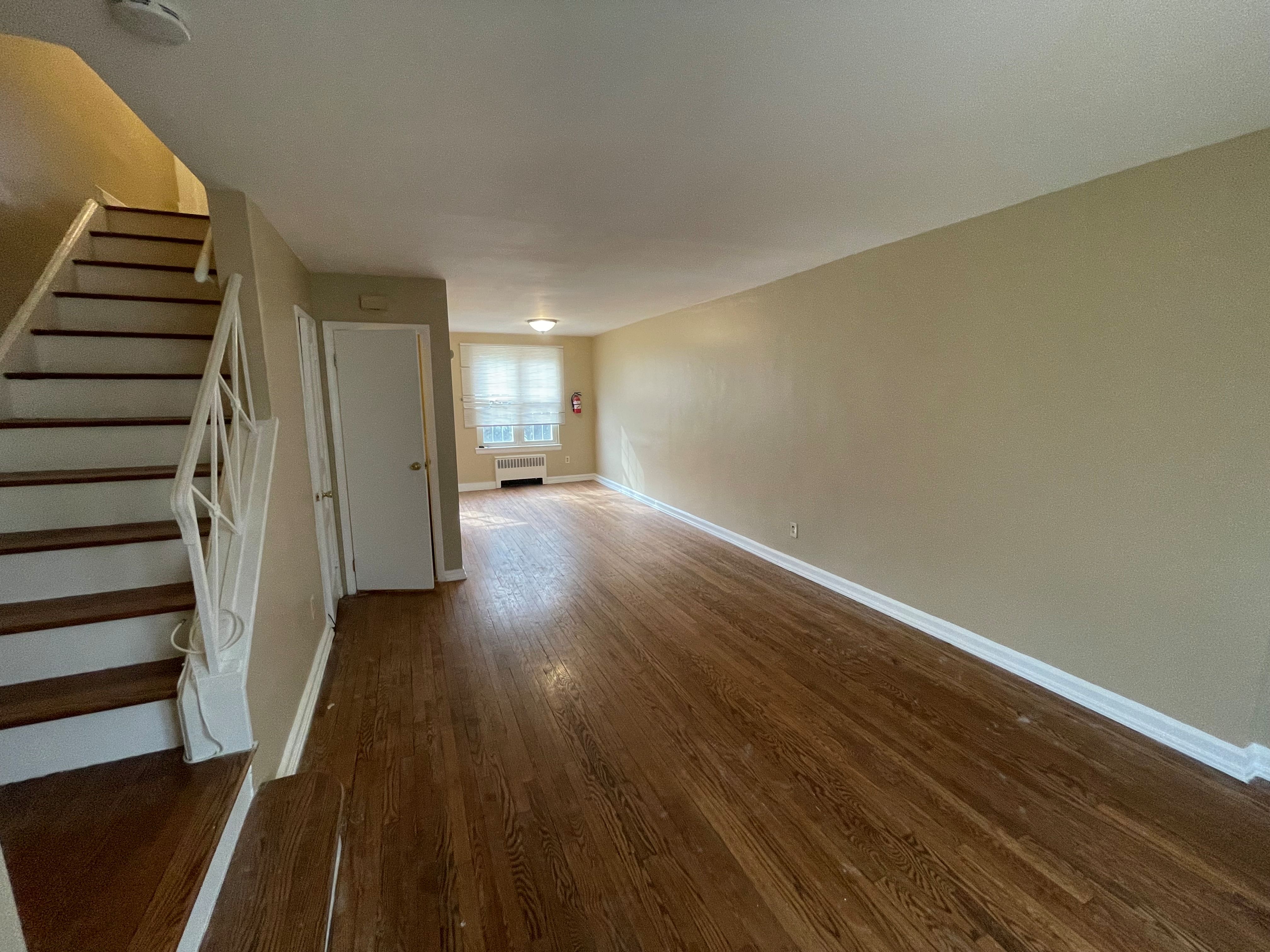 A room with wooden floors and a staircase leading to another room.