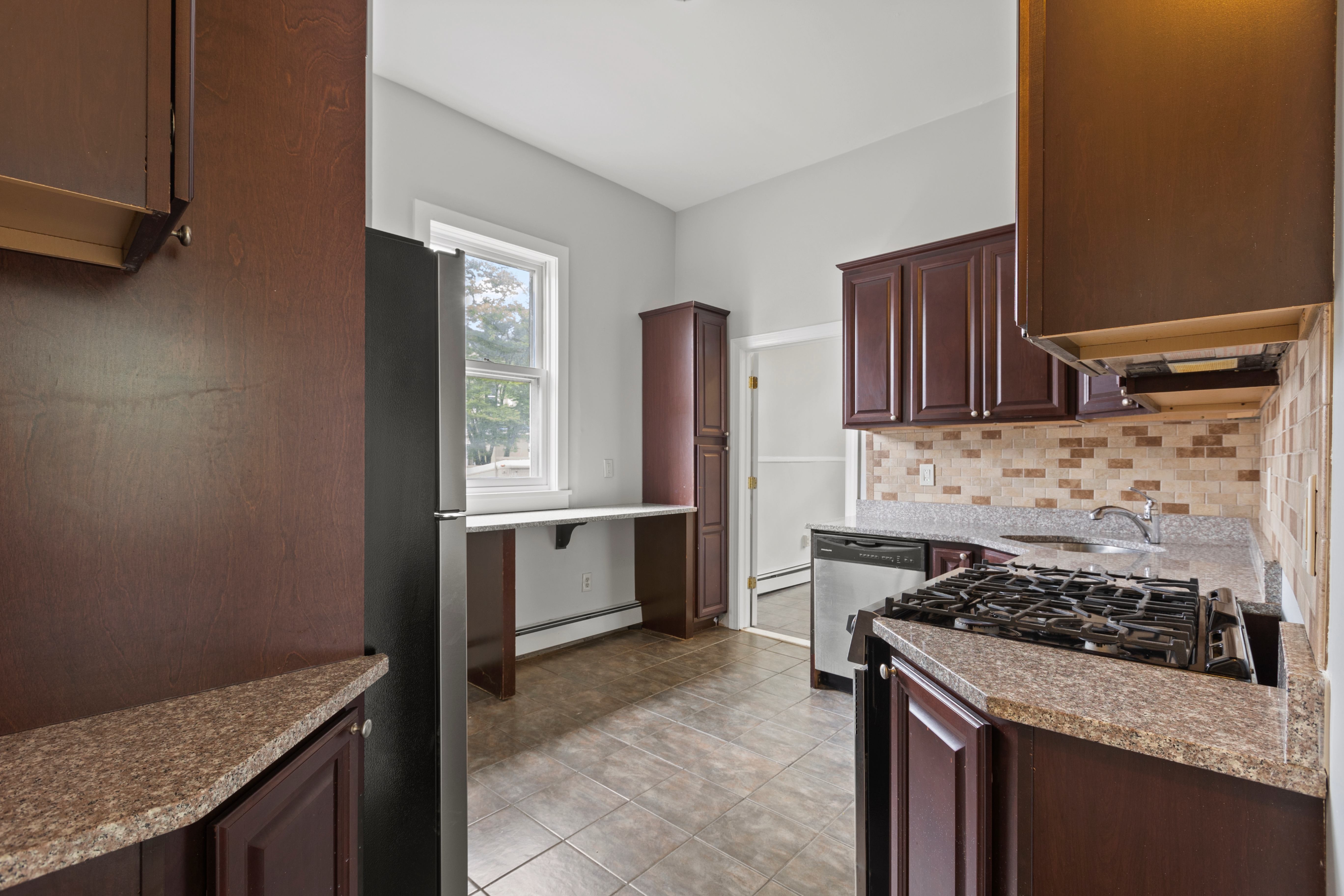 A kitchen with brown cabinets and a tiled floor.