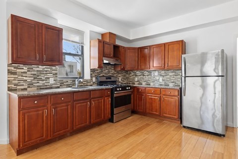 A kitchen with wooden cabinets and a stone backsplash.