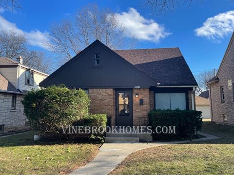 a brick house with a black roof and a sidewalk