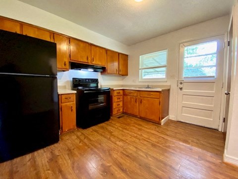 a kitchen with wooden floors and a black refrigerator