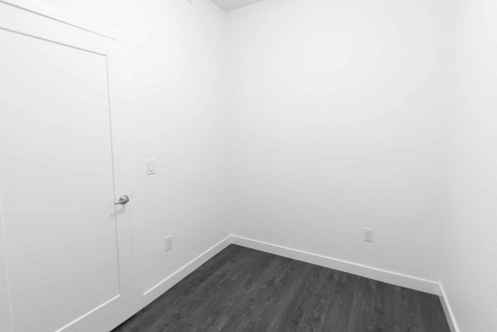 a bedroom with white walls and wood floors and a door