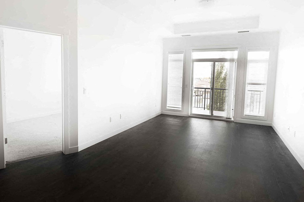 an empty living room with wood floors and a balcony