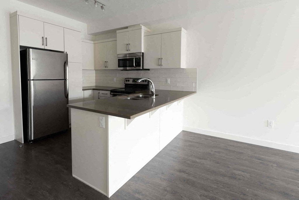 an empty kitchen with white cabinets and stainless steel appliances