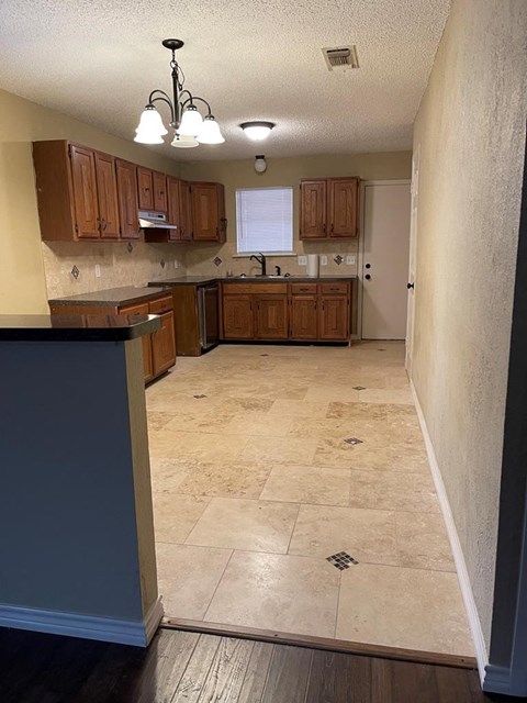 A kitchen with wooden cabinets and a tiled floor.