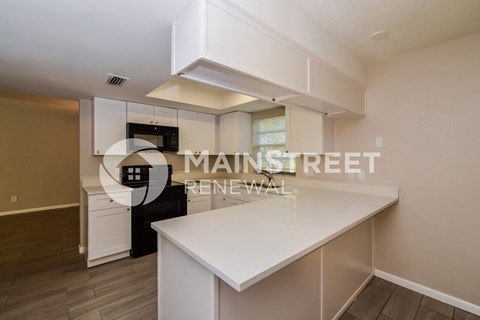 a white kitchen with a white counter top and a black refrigerator