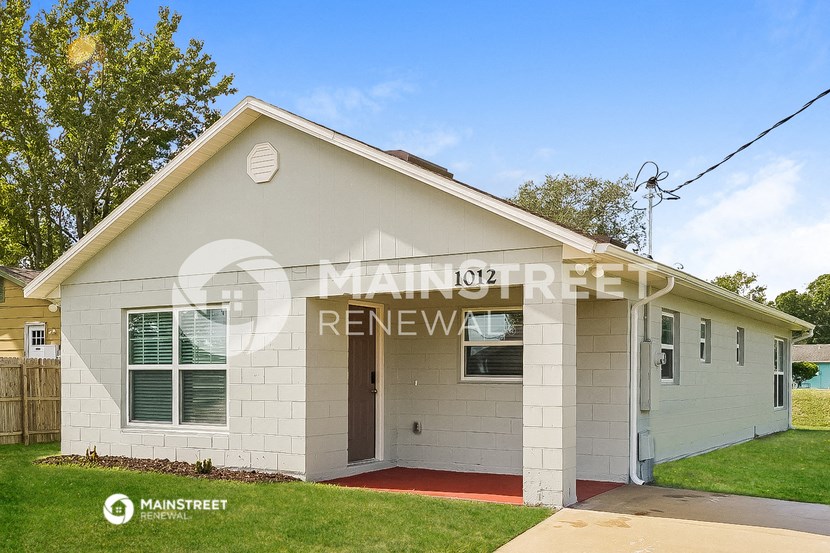 a white brick house with a white front porch and green grass