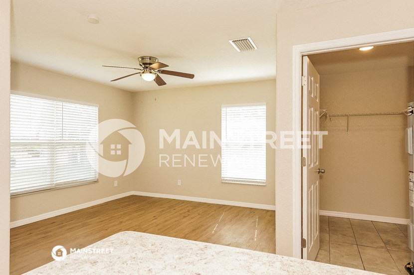 an empty bedroom with a closet and a ceiling fan