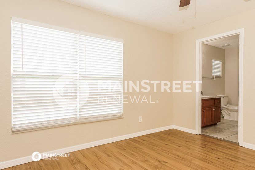 a bedroom with a large window and a door to the bathroom