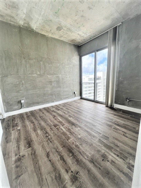 an empty living room with wood floors and a window