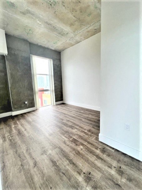 an empty living room with wood flooring and a closet