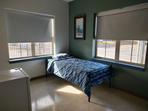 a patient room with a bed and two windows