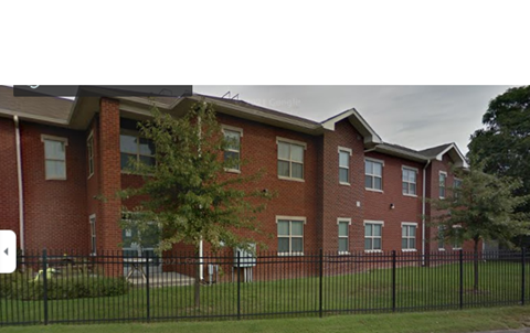 the front of a brick building with a black fence