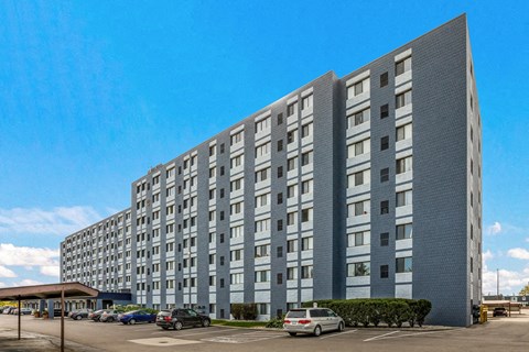 A large grey building with a parking lot in front.