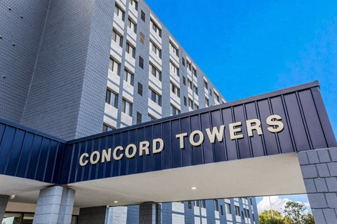 The entrance to the Concord Towers building with a blue sky in the background.