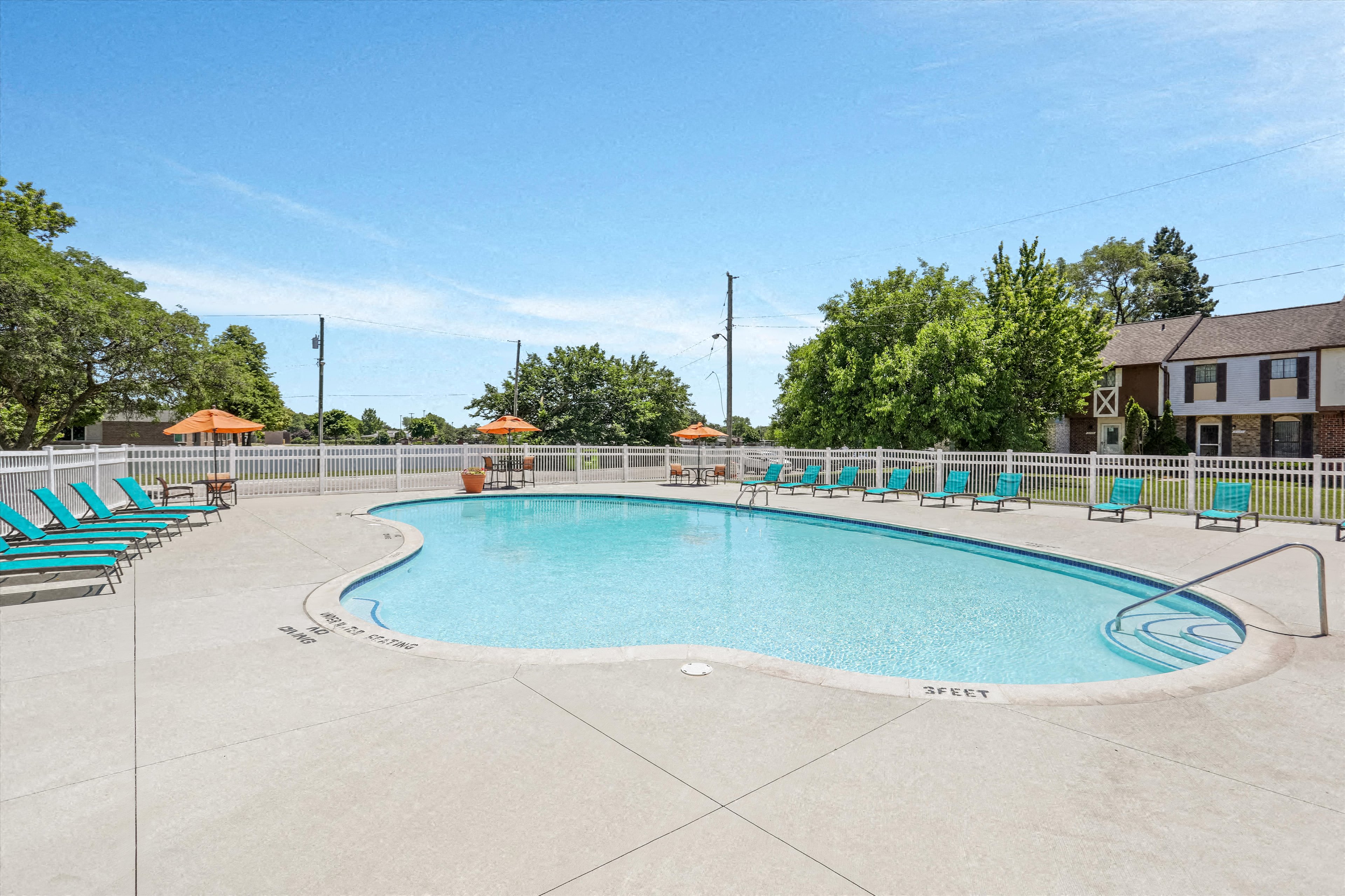 A large outdoor swimming pool surrounded by lounge chairs and trees.