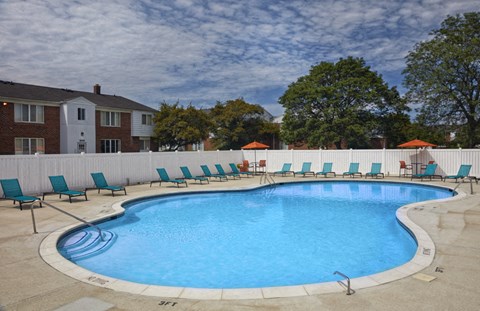 A large outdoor swimming pool surrounded by lounge chairs and umbrellas.