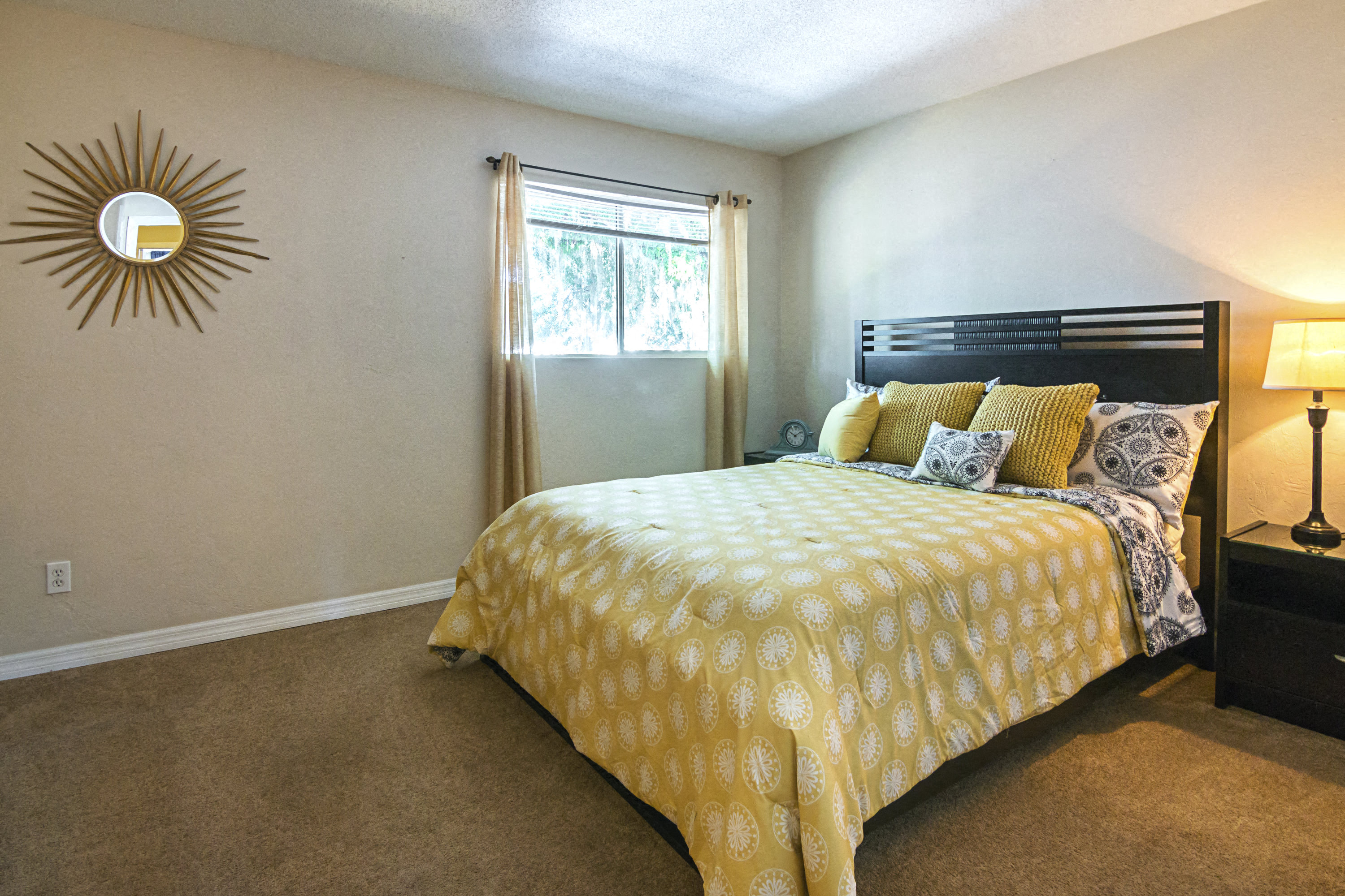 A bedroom with a bed covered in a yellow and white patterned bedspread.