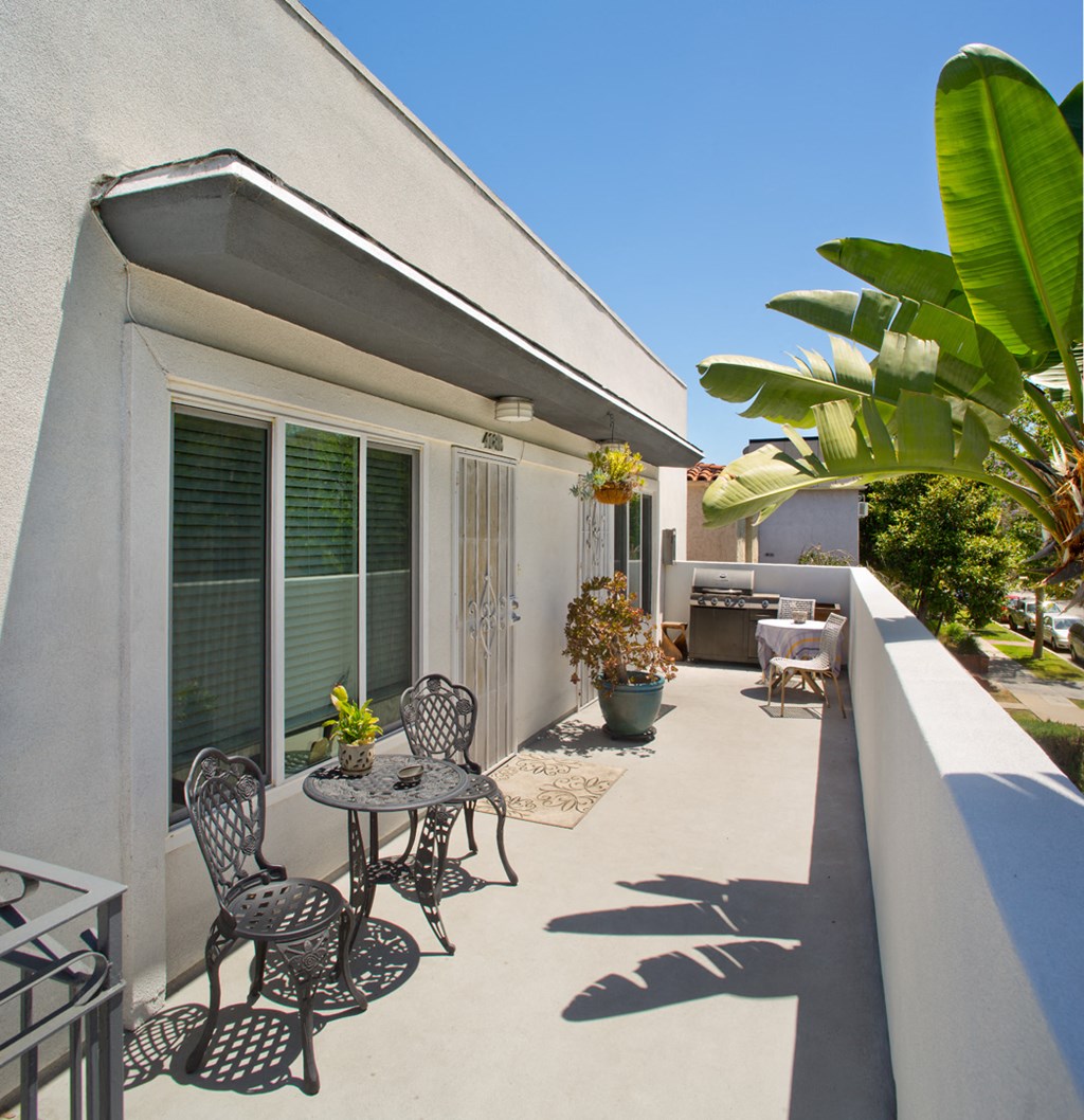 a patio with chairs and a table on the balcony of a house