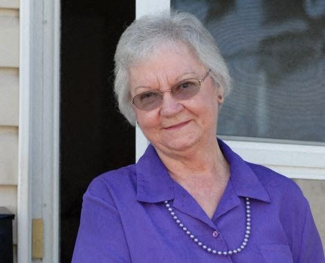 an older woman wearing glasses and a purple shirt