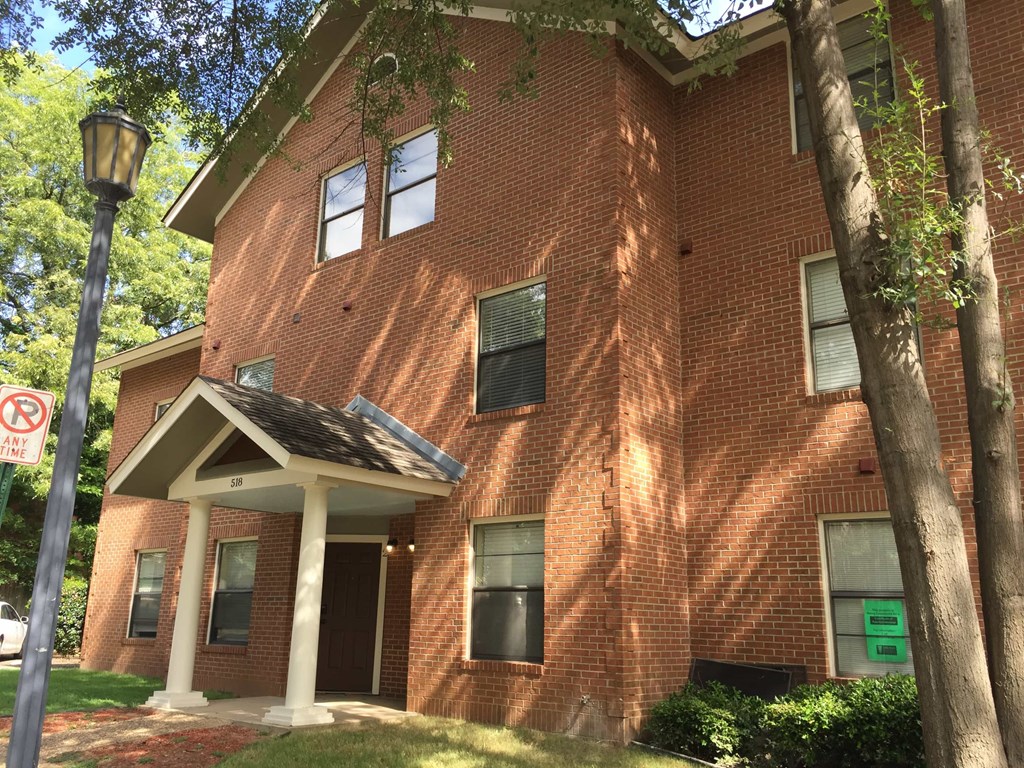 a red brick building with a porch and a street light