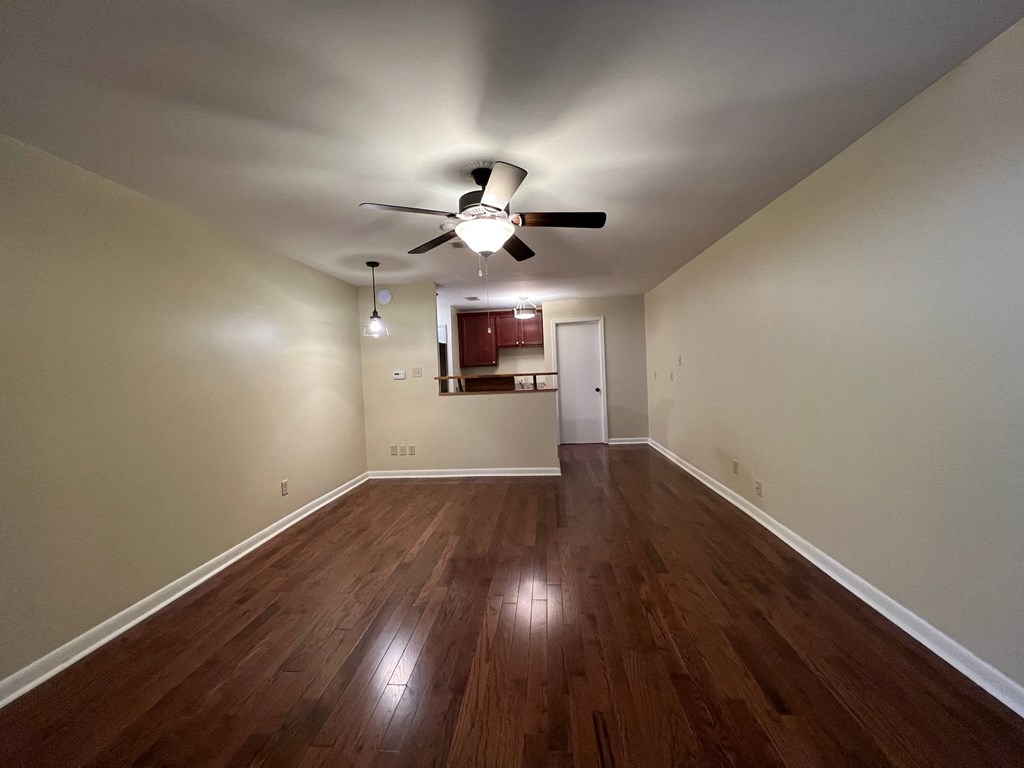 an empty living room with hardwood floors and a ceiling fan