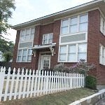 a brick house with a white fence in front of it