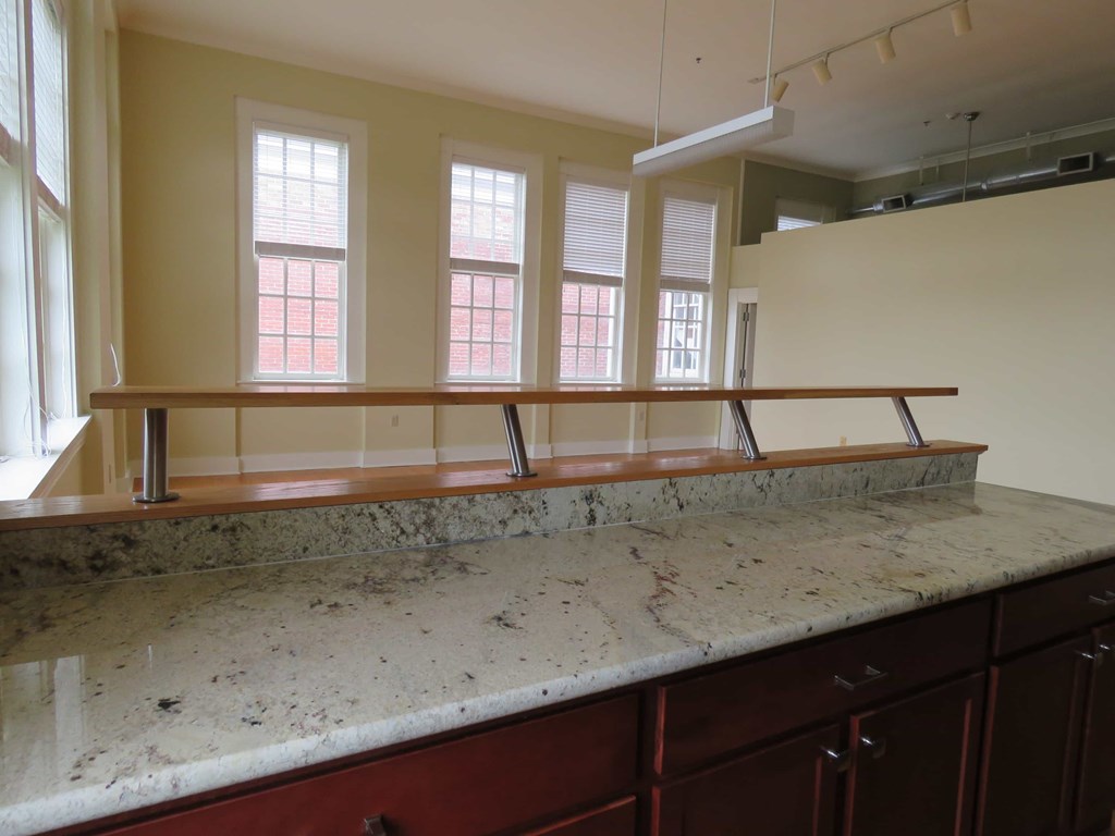 an empty kitchen with a counter top and a row of windows