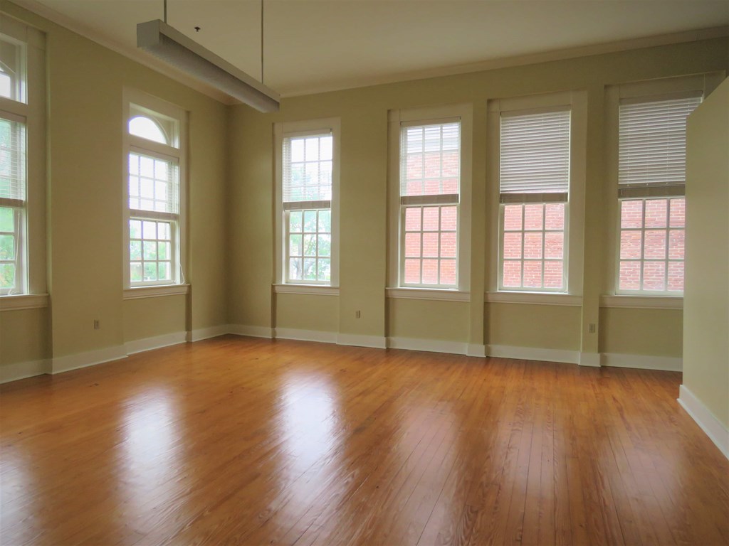an empty living room with wood floors and windows
