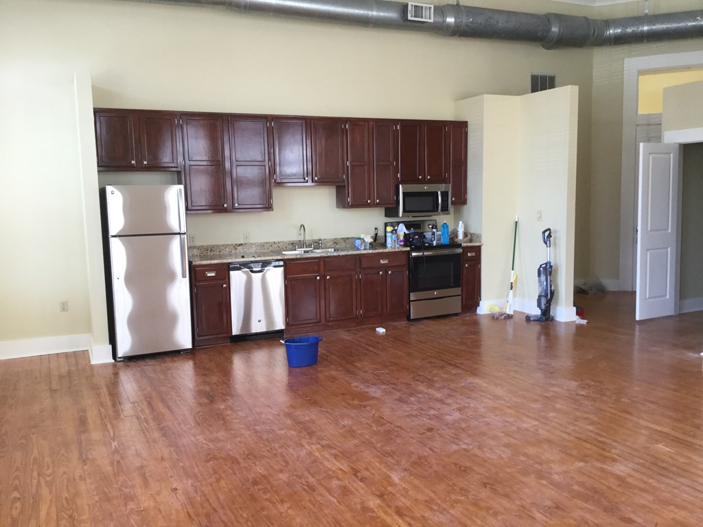 an empty kitchen with wooden floors and a refrigerator