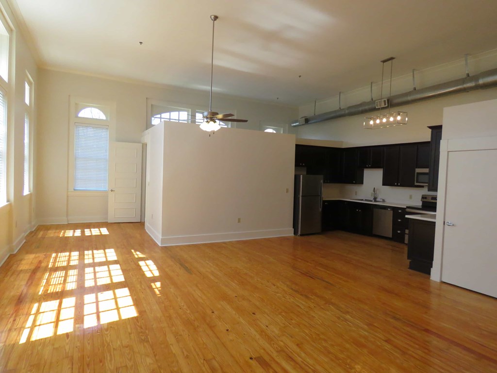 an empty living room and kitchen with wood floors