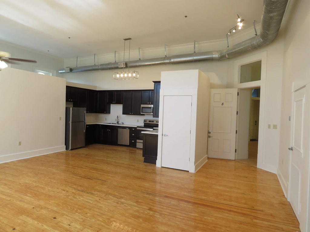 an empty living room and kitchen with a wood floor
